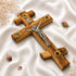 Wooden cross with a silver Jesus figure on a white fabric background
