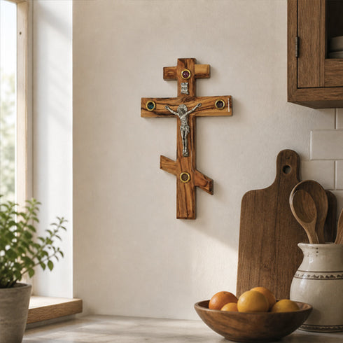 Wooden crucifix on a wall in a kitchen setting with a bowl of fruit and utensils.