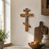 Wooden crucifix on a wall in a kitchen setting with a bowl of fruit and utensils.