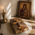 Wooden cross on an open book with a religious icon and candle in the background