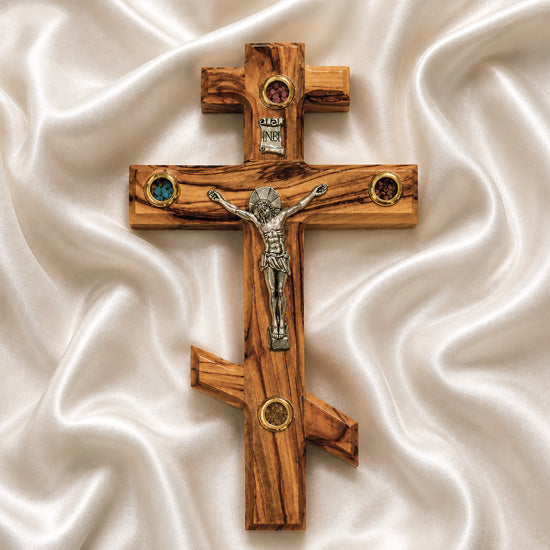 Orthodox wooden cross with Jesus Christ figure on a white fabric background