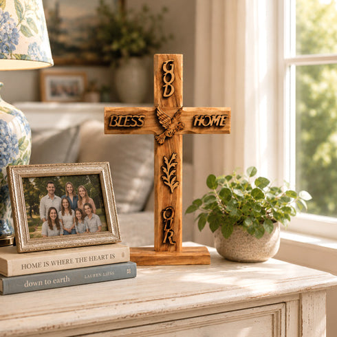 Wooden cross with engraved text on a table with books and a family photo
