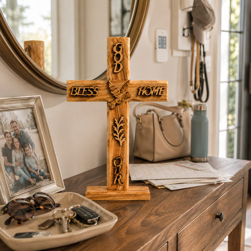 Wooden cross with engraved text on a wooden surface, surrounded by personal items.