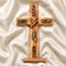 Wooden cross with engraved text and designs on a white fabric background