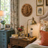 Decorative wall "God Bless our Home" plaque above a table with a lamp and books in a bedroom.