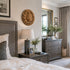 Neatly arranged bedroom with bed, nightstand, dresser, and decorative elements.