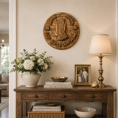 Decorative console table with a lamp, flowers, books, and a framed photo against a wall with a decorative plaque.