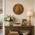 Decorative console table with a lamp, flowers, books, and a framed photo against a wall with a decorative plaque.