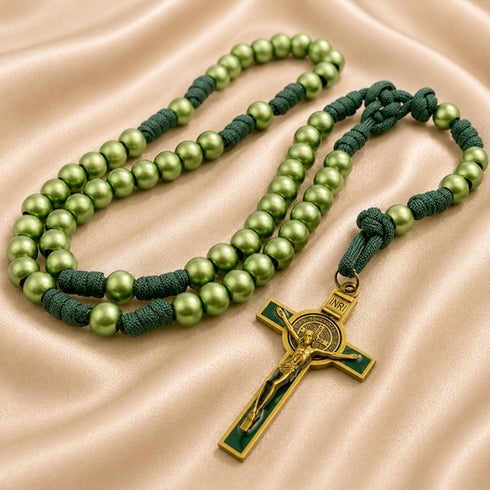 A green rosary with dark green knotted cord and a gold-tone crucifix, on a satin fabric.