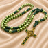 A green rosary with dark green knotted cord and a gold-tone crucifix, on a satin fabric.