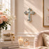 Decorative cross on a wall with flowers, books, and candles in a room.