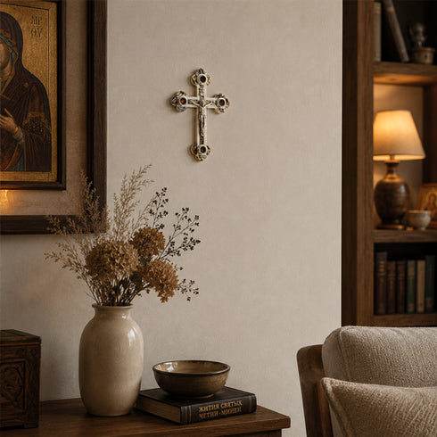 Nestled corner of a room with a cross on the wall, vase with flowers, books, and a chair.