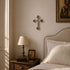 Orthodox style bedroom with wooden nightstand, lamp, and framed pictures on a beige wall.