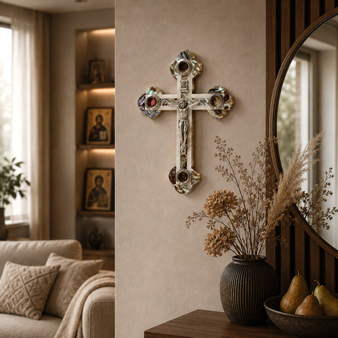 Decorative cross on a wall in a living room with a vase and pears on a table.