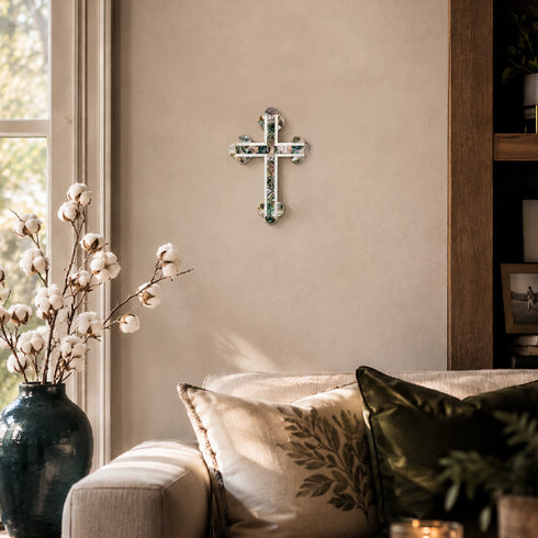 Living room with a cross on the wall, a vase with cotton branches, and a couch with decorative pillows.