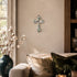 Living room with a cross on the wall, a vase with cotton branches, and a couch with decorative pillows.