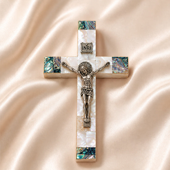 Small olive wood cross with crucifix, Nacre inlay and INRI plaque, laid on white surface.