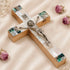 Olive Wood Latin Crucifix with Mother of Pearl shell adornments, placed on a white fabric with flowers.