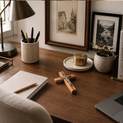 Wooden desk with office supplies, a cross, and framed pictures on a wall.