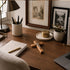 Wooden desk with office supplies, a cross, and framed pictures on a wall.