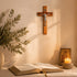 Wooden cross, open book, candle, and icon on a table with a neutral background