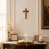Decorative interior with a lamp, open book, candle, and framed picture on a table against a wall with a crucifix and painting.