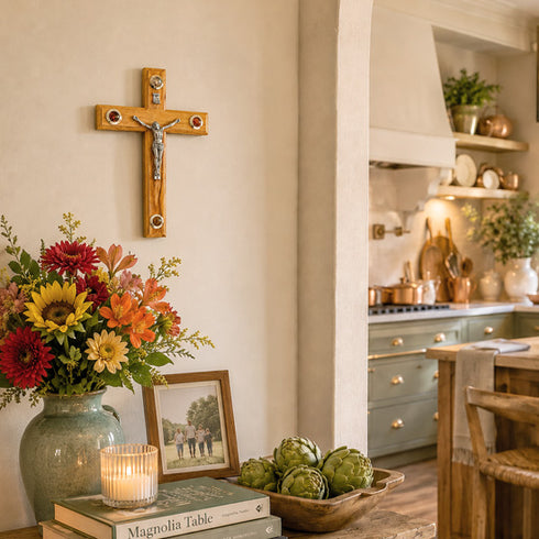 Kitchen interior with a crucifix on the wall, flowers, books, and a candle.