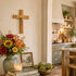 Kitchen interior with a crucifix on the wall, flowers, books, and a candle.