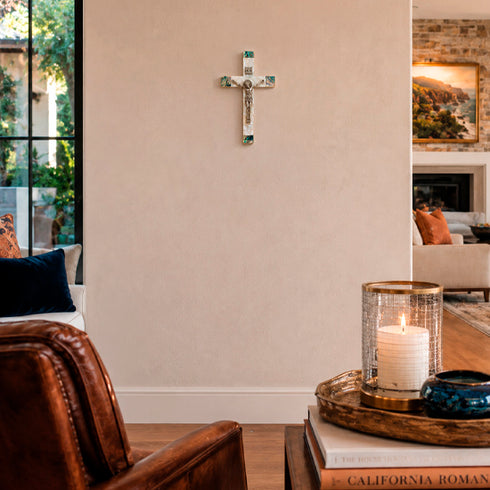 Living room with a cross on the wall, candle in a holder, and books on a coffee table.