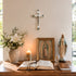 Religious items including a cross, statue, and open book on a table with a neutral background.