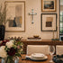 Dining room with a table set for a meal, flowers, cross and wall art.