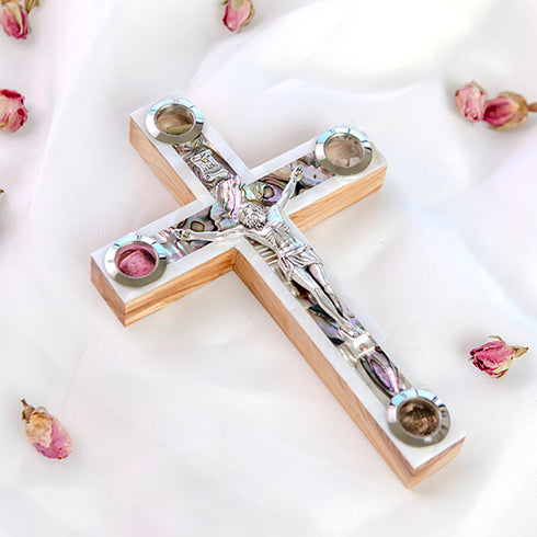 A handcrafted wooden Latin cross with a silver crucifix made of olive wood, adorned with mother of pearl, holy soil, olive leaves, dried flowers, and incense.