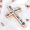 A handcrafted wooden Latin cross with a silver crucifix made of olive wood, adorned with mother of pearl, holy soil, olive leaves, dried flowers, and incense.