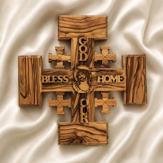Handmade Olive wood Jerusalem Cross with "God Bless Our Home" and Christs portrait engraved set against a clean white background.
