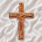 Wall-hanging olive wood Latin cross engraved with a dove and "GOD BLESS OUR HOME", on a white backdrop with rose petals.