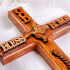 Latin olive wood cross hand-crafted and engraved with “God Bless Our Home” and a dove, laid on white background.