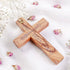 Back of a hand-crafted Latin olive wood cross with Stations of Cross and "Jerusalem" printed, on white cloth with petals.
