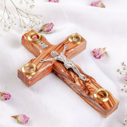 Ornate latin cross with Four Elements and metal crucifix, laid on white surface with rose petals around it.