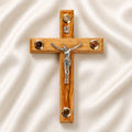 Medium size all-hanging olive wood Latin cross with carved edges, crucifix, Four Elements, on a white backdrop with petals.