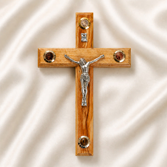 Medium size all-hanging olive wood Latin cross with carved edges, crucifix, Four Elements, on a white backdrop with petals.