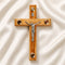 Medium size all-hanging olive wood Latin cross with carved edges, crucifix, Four Elements, on a white backdrop with petals.