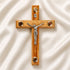 Medium size all-hanging olive wood Latin cross with carved edges, crucifix, Four Elements, on a white backdrop with petals.