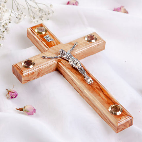 A hand-crafted wooden Latin crucifix with Four Elements, mounted on a white fabric.