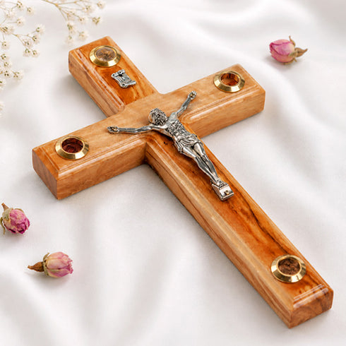 A hand-crafted wooden Latin crucifix with Four Elements, mounted on a white fabric.