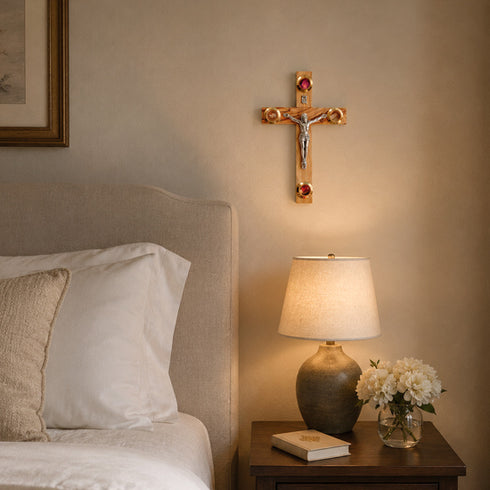 Bedroom with a crucifix on the wall, lamp, and flowers on a nightstand.