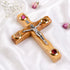 A handcrafted wooden crucifix with a natural olive wood, featuring Four Elements, on white surface.