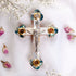 Budded olive wood cross with silver crucifix and Nacre lying flat on white background with scattered rose petals.