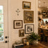 Decorative wall with framed pictures, a cross, and a plant in a home setting.