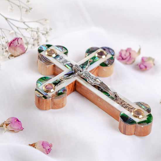 Olive wood cross with crucifix and Mother of pearl highlights on white backdrop.