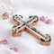 Olive wood cross with crucifix and Mother of pearl highlights on white backdrop.